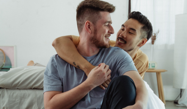 Young male couple hugging at home